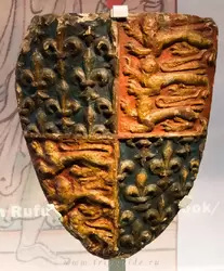 Королевский герб, конец 1300-х, каменный щит из Ратуши времён, когда Эдвард III предъявлял права на французский трон, поэтому герб включает лилии Бурбонов, а также трёх львов Англии