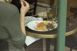 Пожилая француженка причмокивая потребляет тар-тар на завтрак (сырое рубленое мясо)